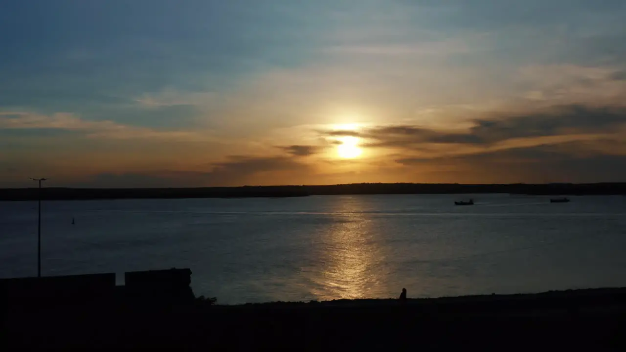 Stunning aerial drone dolly out shot of a golden sunset reflecting onto the water and the camera passing over a famous historical military fort in Joao Pessoa Brazil