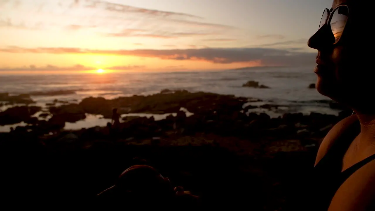 Profile shot of female petting dog ocean sunset reflection in sunglasses