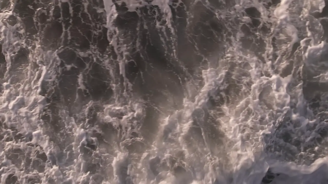 Aerial slow motion birds eye view above foaming ocean waves