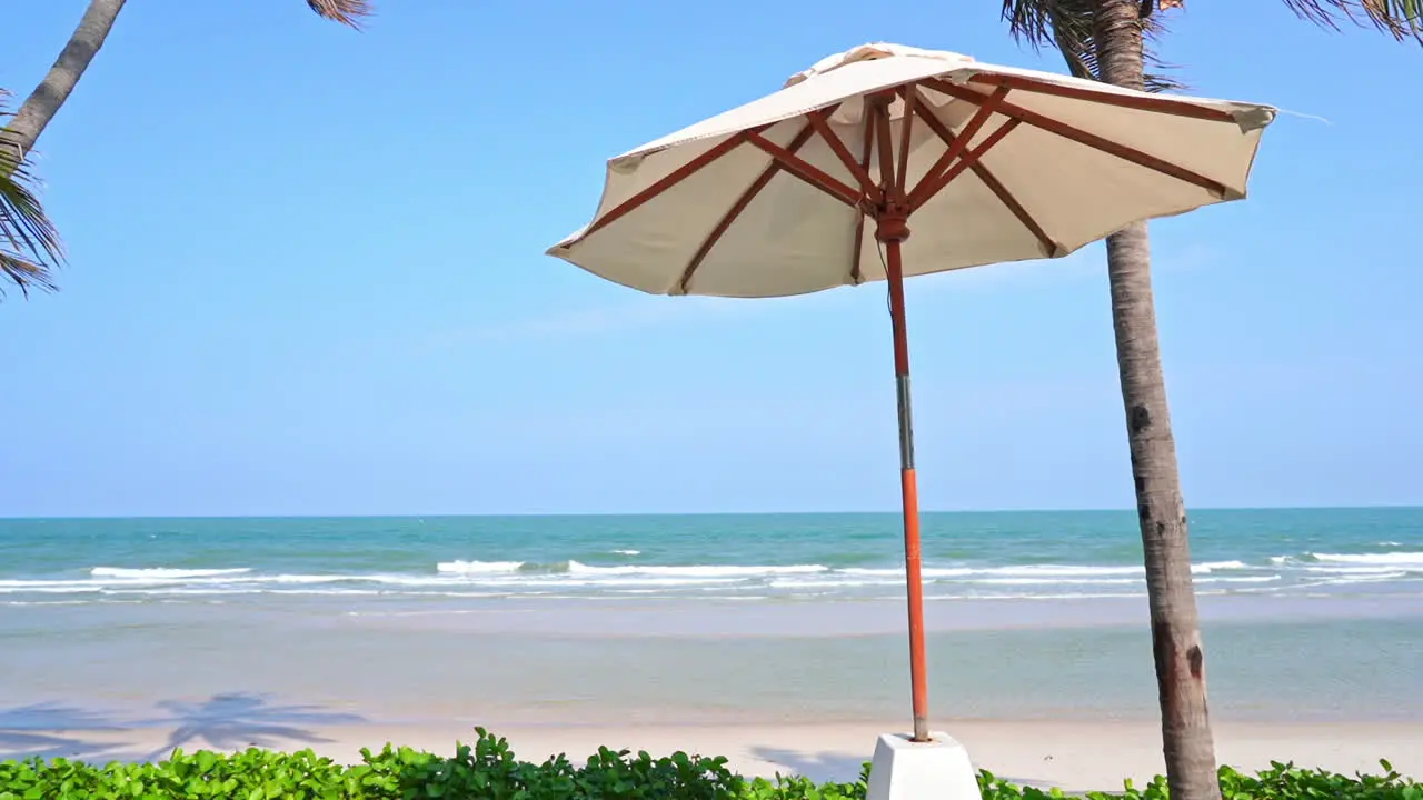 A single beach umbrella on the beach rustles in the tropical breeze