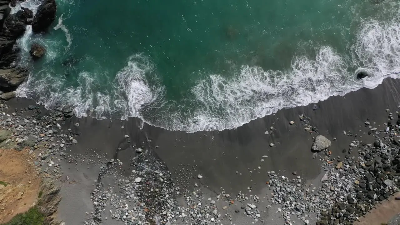 Top Down View Of Waves Splashing On Rocky Shore aerial drone shot