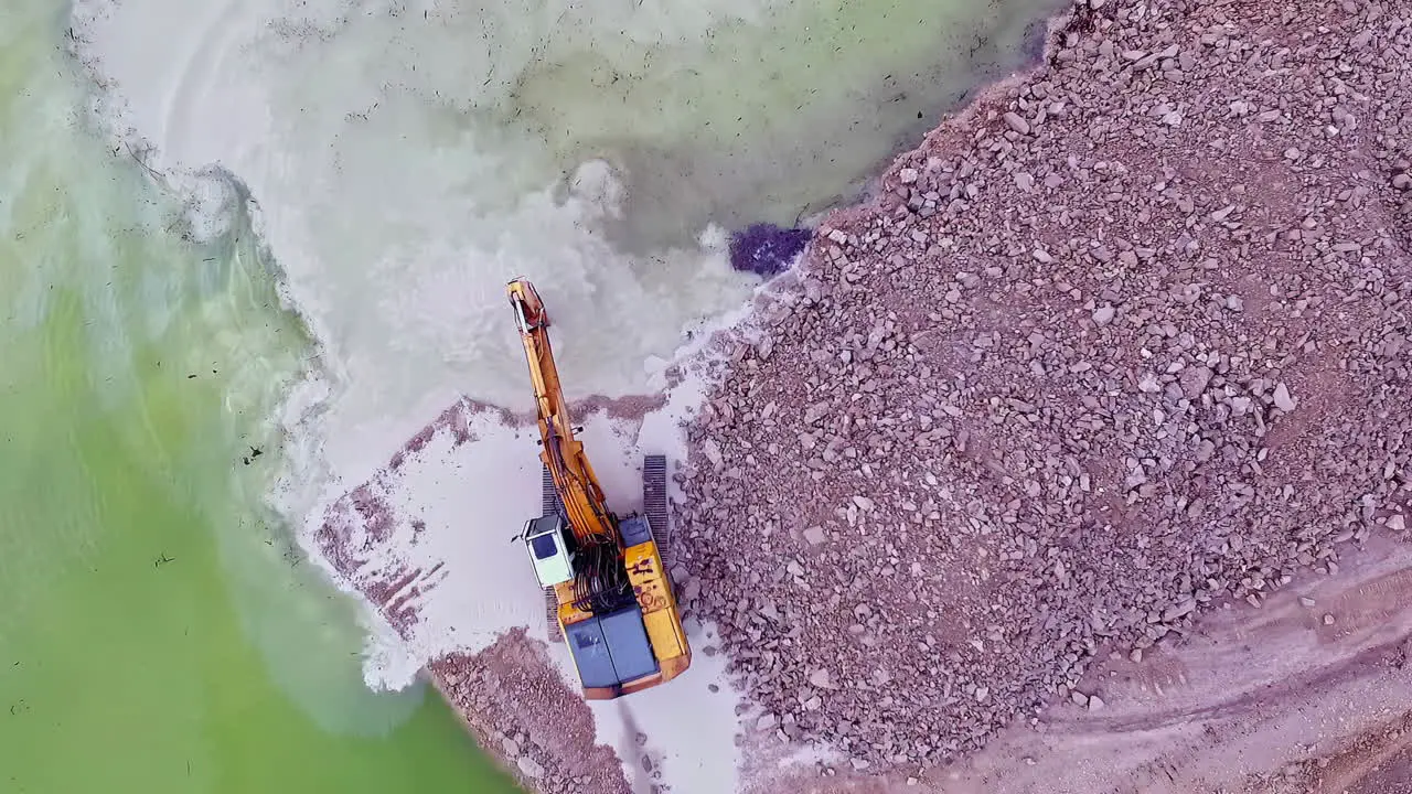 Birdseye view areal shot of a industrial loader digging for sand in the ocean and putting on the beach