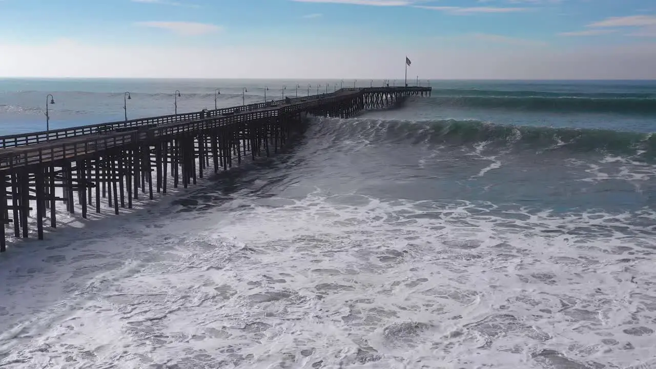 Aerial over huge waves rolling in over a California pier in Ventura California during a big winter storm suggests global warming and sea level rise or tsunami 7