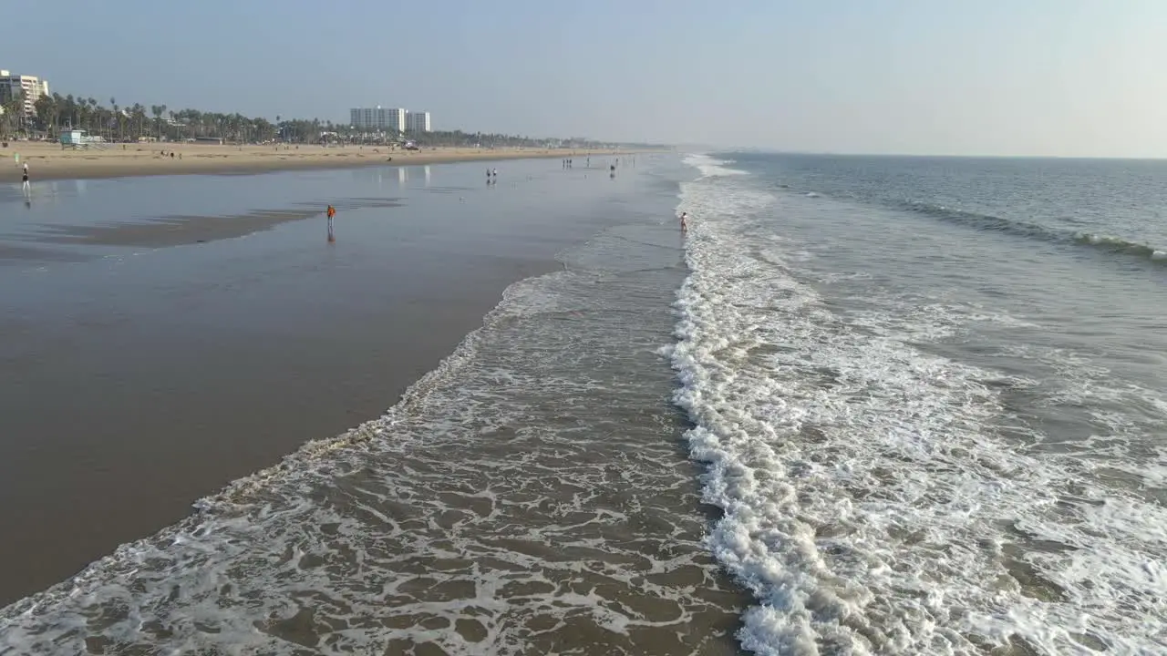 Waves rolling at the beach in Los Anegeles California people walking by the beach