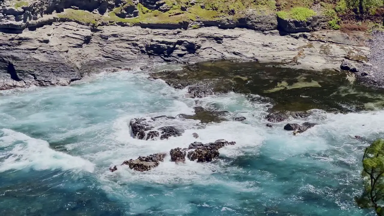 Cinematic long lens panning shot of the ocean tide crashing into rocks at Kilauea Point on the northern edge of Kaua'i in Hawai'i