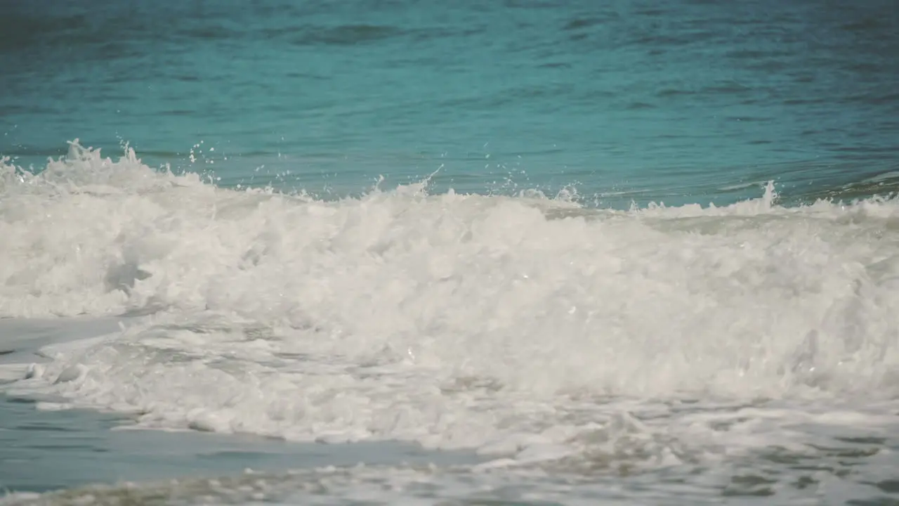 Slow Motion shot of Beautiful Blue Giant Ocean Wave Crashing at golden sandy beach