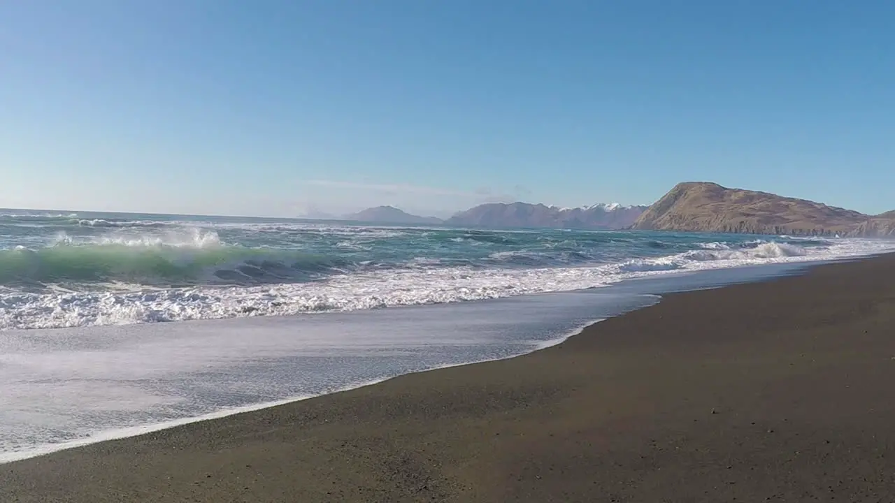 A beautiful sunny day with clear blue skies along a sandy beach with mountains in the distance on Kodiak Island Alaska