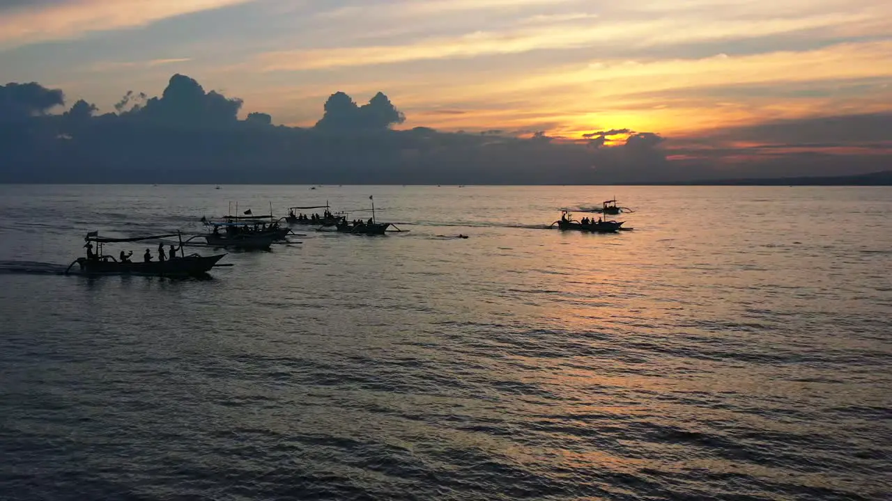 aerial of mass tourism with tourist boats chasing dolphins in tropical waters of Lovina Bali Indonesia at sunrise