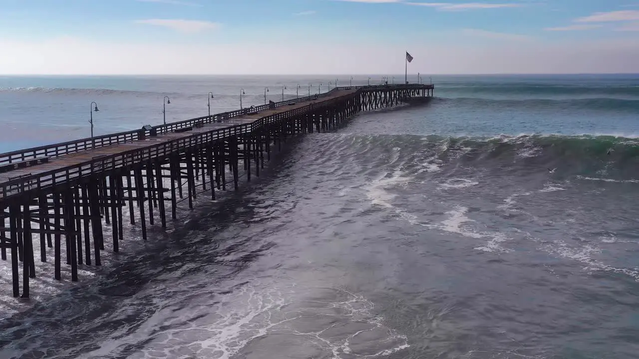 Aerial over huge waves rolling in over a California pier in Ventura California during a big winter storm suggests global warming and sea level rise or tsunami 6