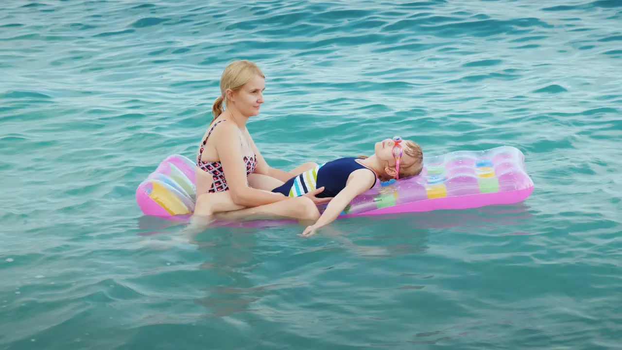 A Young Family Is Relaxing On The Waves On An Inflatable Mattress