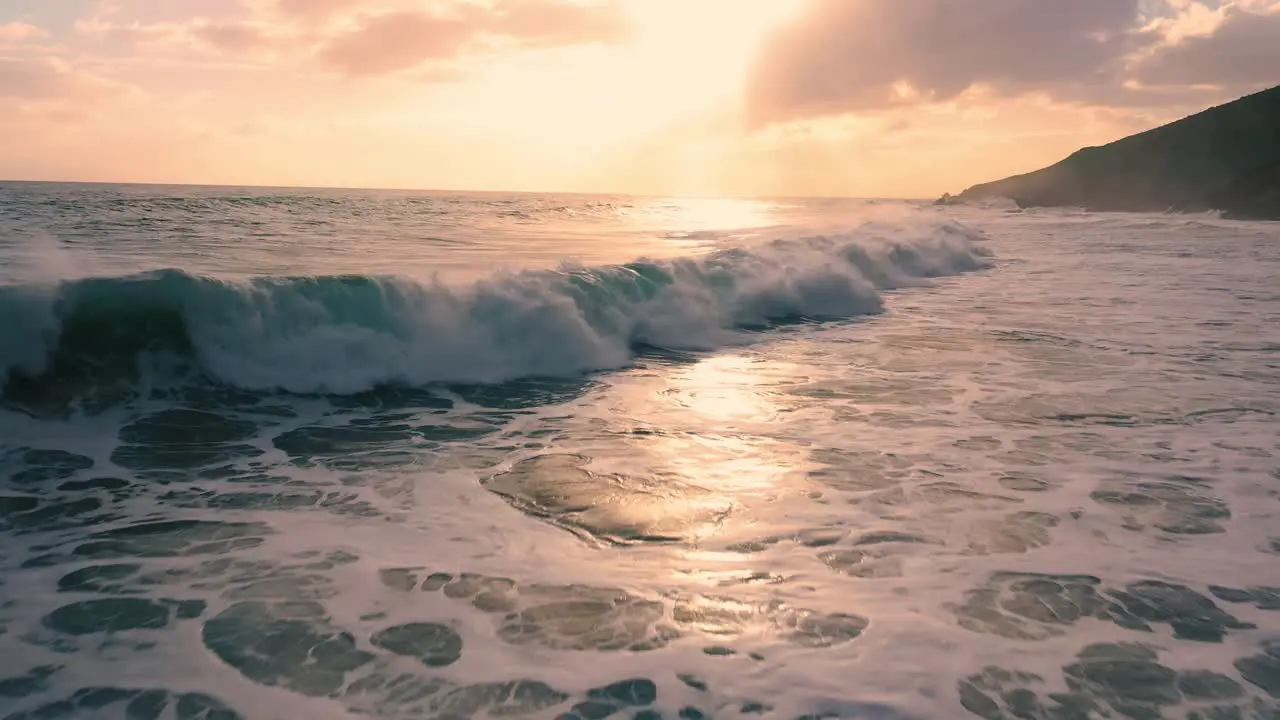 Flying low over the crashing ocean waves at sunset