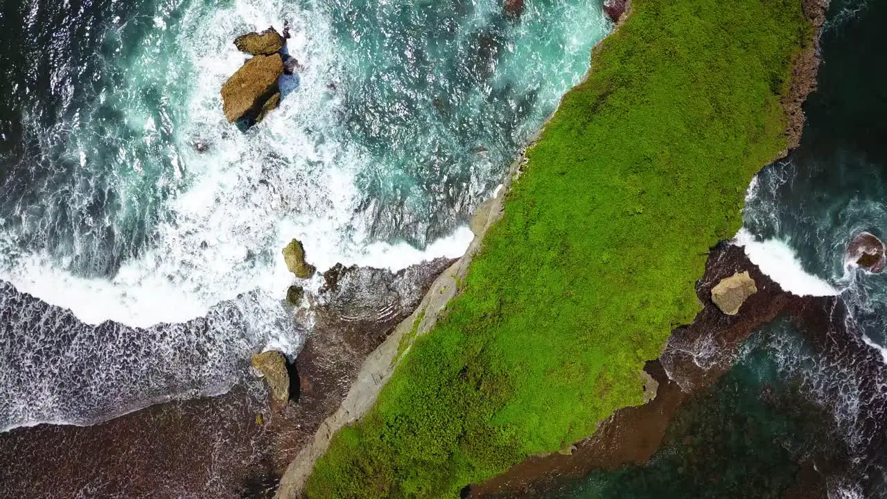 Overhead view of tropical ocean breaking waves and green forest in Indonesia