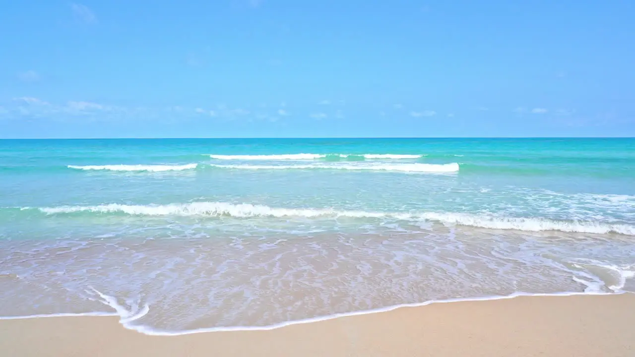 Waves from a turquoise ocean wash up on a golden beach