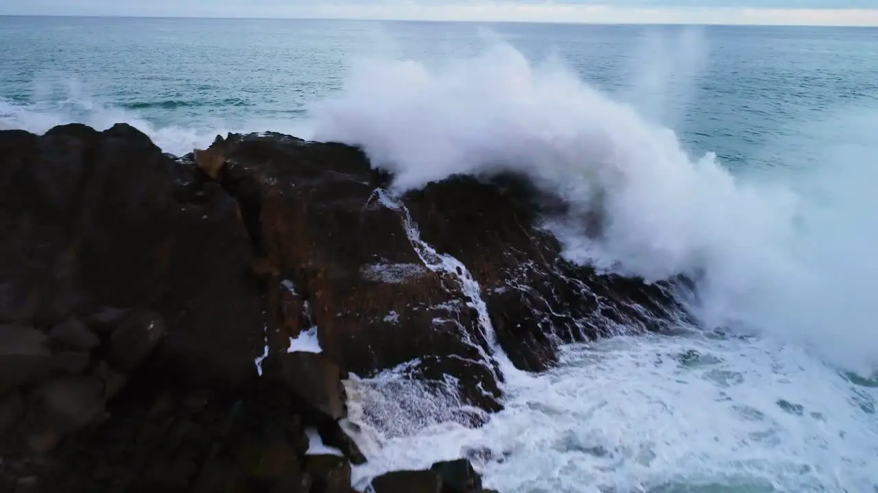 Drone pullback on wave crashing on rocks