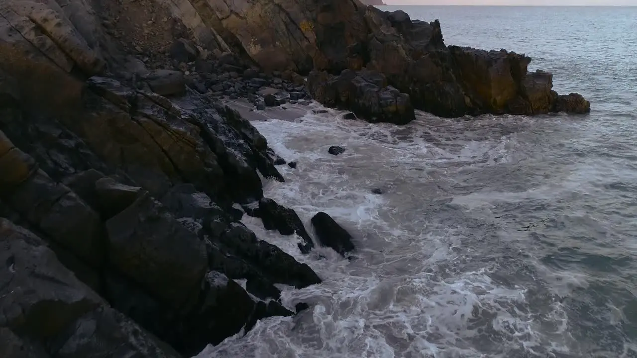 Ocean waves crashing on rocks at sunset