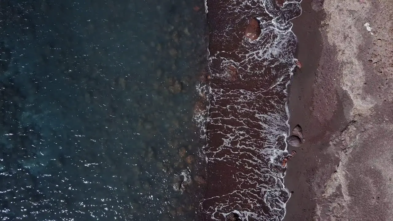 Top down aerial shot over red sand beach on Greek island of Santorini 4K