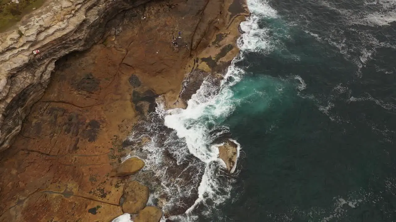 Aerial view moving south to north of Maroubra Beach north headland with unrecognisable fisherman on rocks