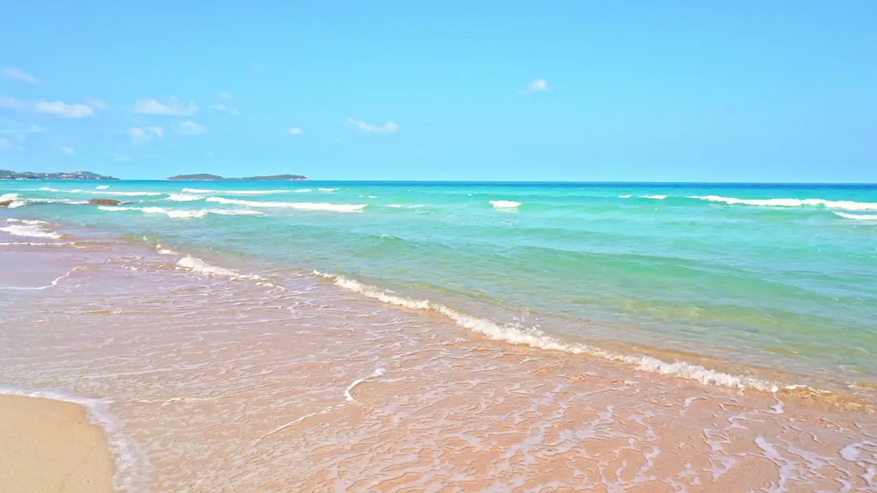 Waves from turquoise ocean waters wash up on a golden sandy beach