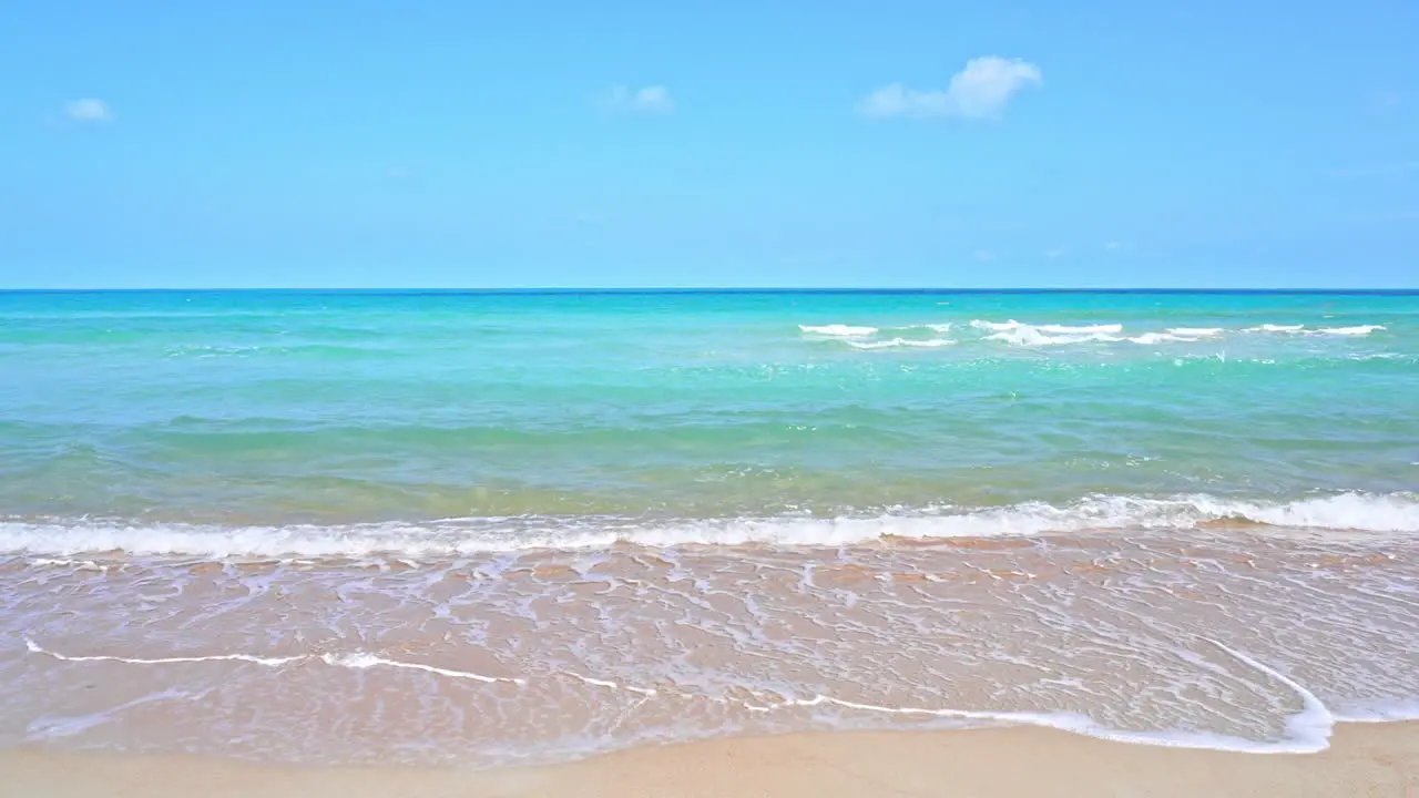 Ocean waves wash up on the golden sand of a tropical beach