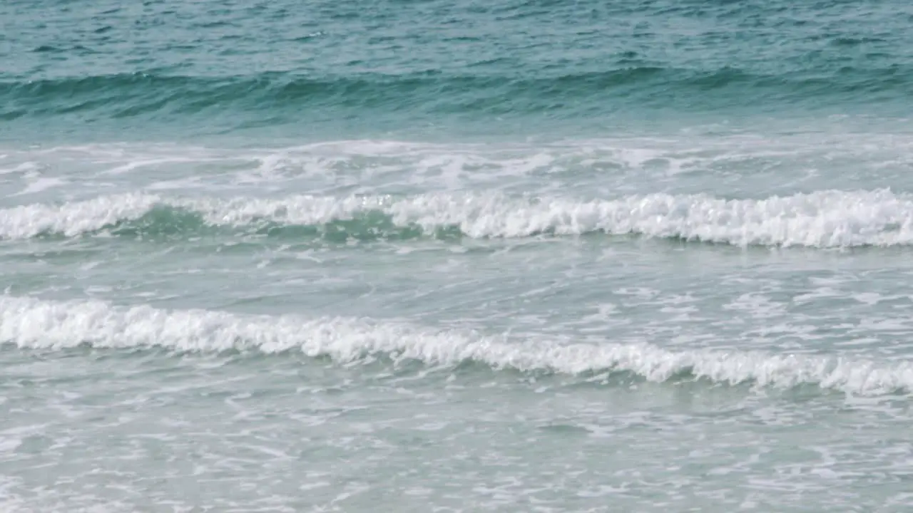 Small waves crashing on the beach in slow motion