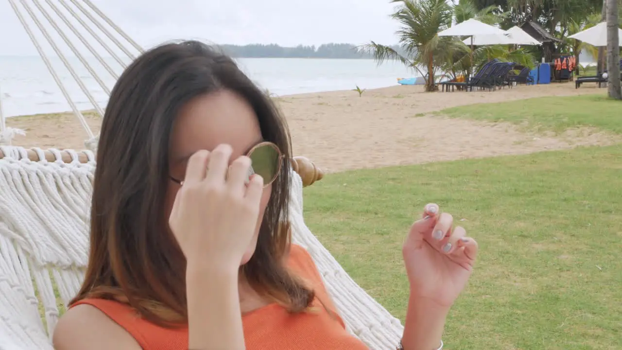 asian woman relaxing and on hammock near beach under coconut tree in vacation holiday time