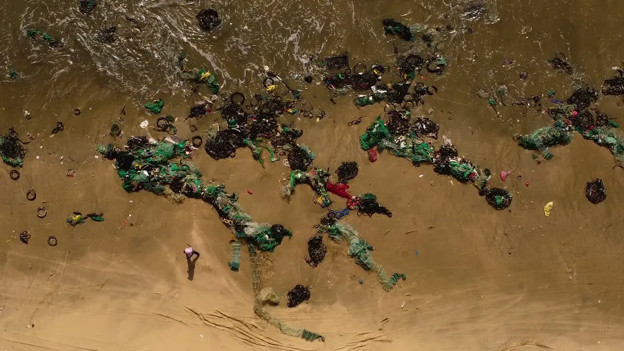 aerial top down of ocean pollution plastic fishing net on ocean tropical sandy beach after monsoon storm industrial agricultural marine pollution concept