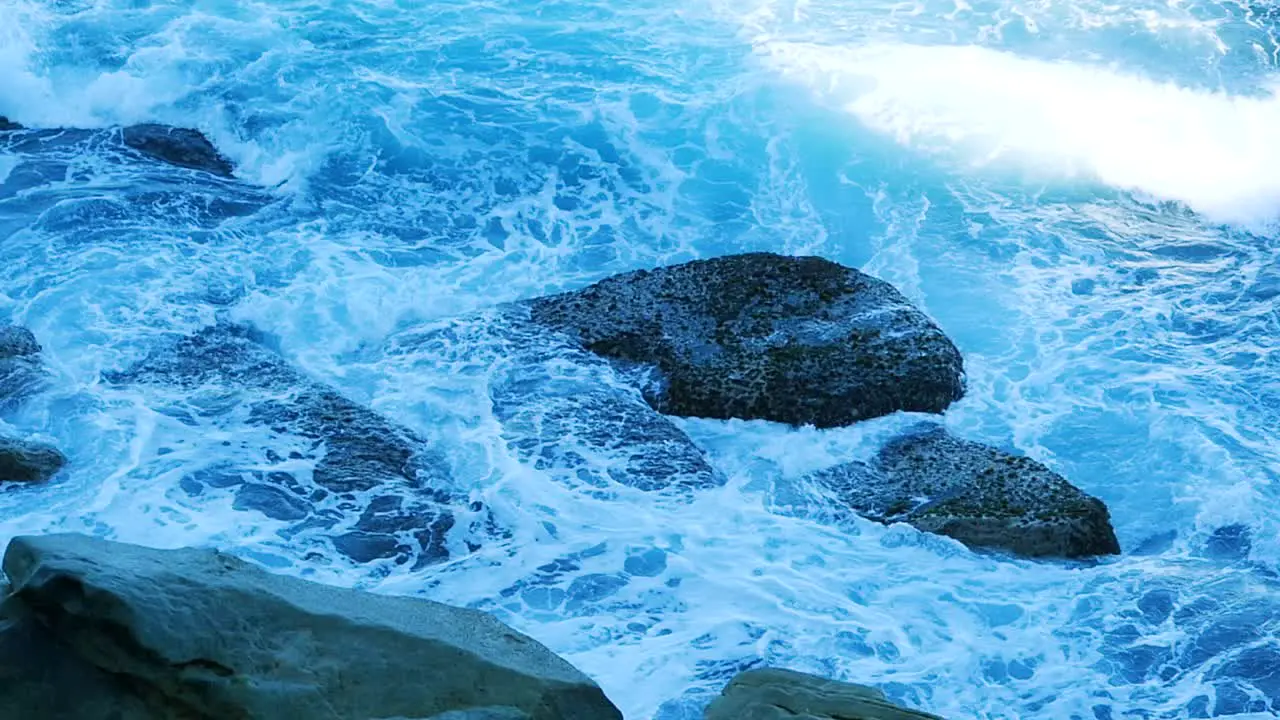 Abstract Of White Foamy Waves Crashing Over Rocks During Summer