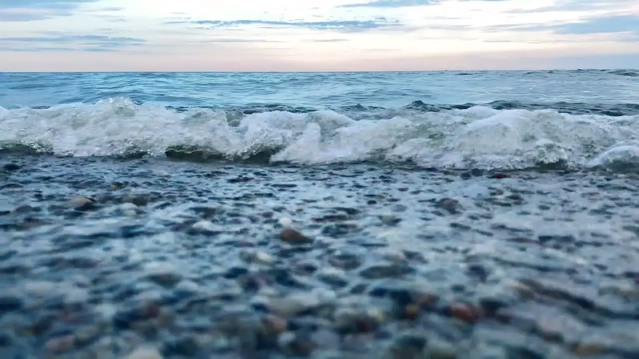 Low angle shot of crashing waves at the sea shore during daytime after sunset close up