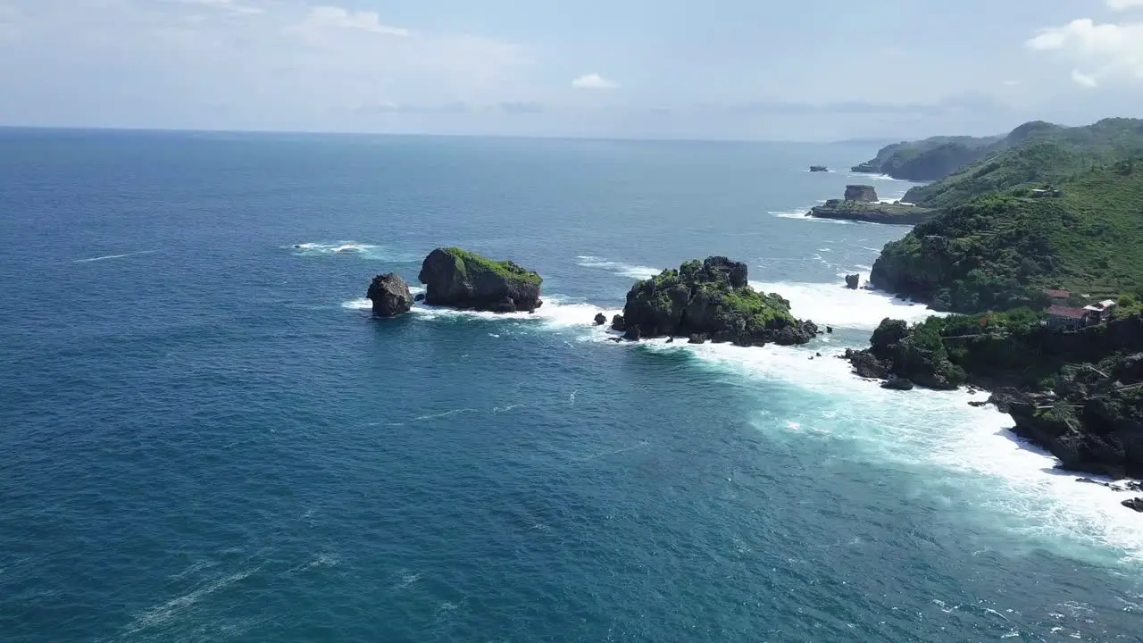 Drone shot of rock islands on the beach hit by waves during sunny day TIMANG ISLAND YOGYAKARTA INDONESIA