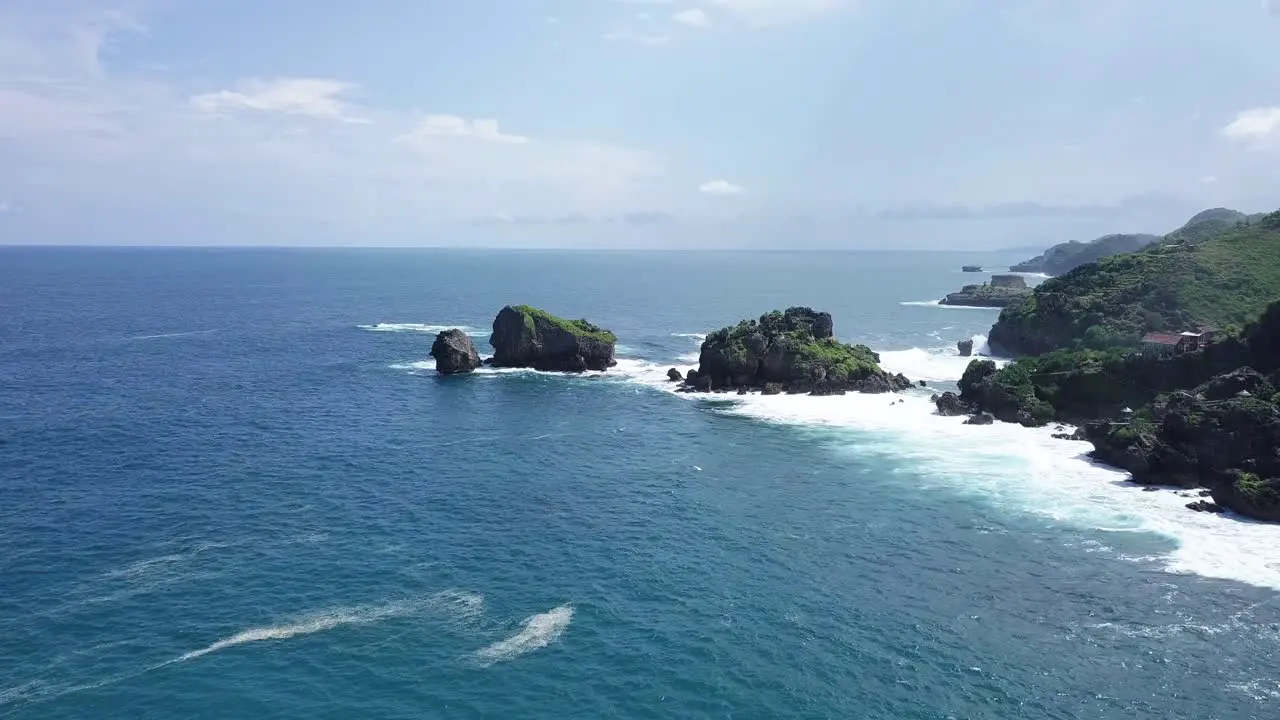 Drone shot of two rock island on the beach hit by waves during sunny day TIMANG ISLAND YOGYAKARTA INDONESIA