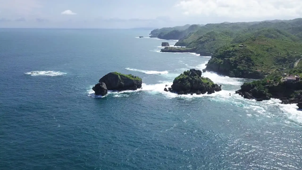 Aerial view of coral island with overgrown by trees in ocean hit by waves during sunny day TIMANG ISLAND YOGYAKARTA INDONESIA