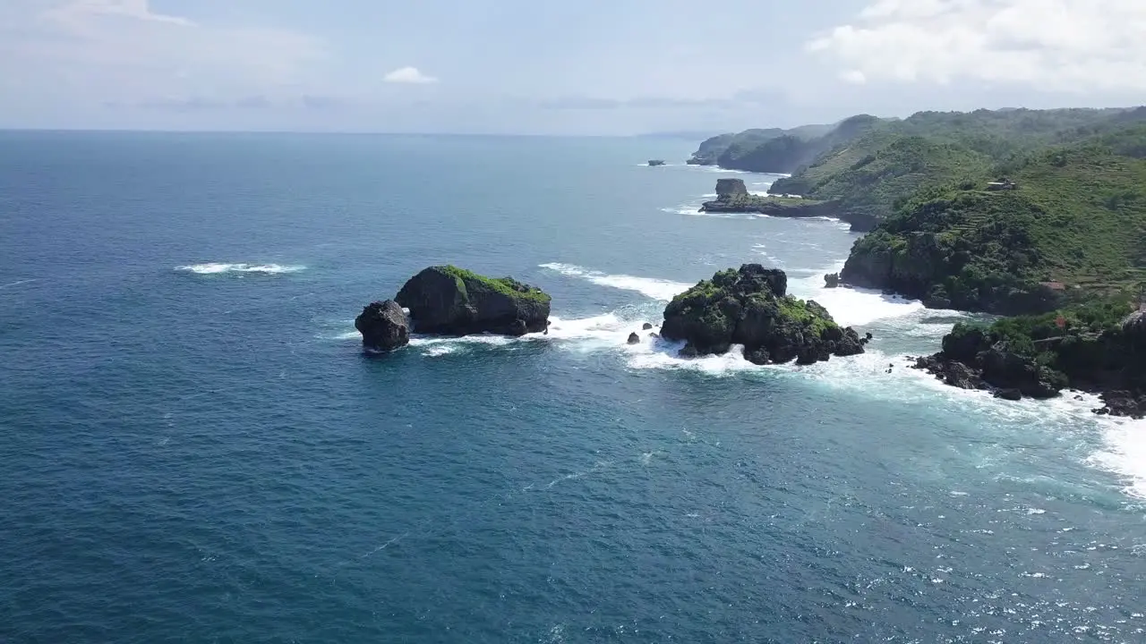 Aerial view of rock island in ocean hit by waves during sunny day TIMANG ISLAND YOGYAKARTA INDONESIA