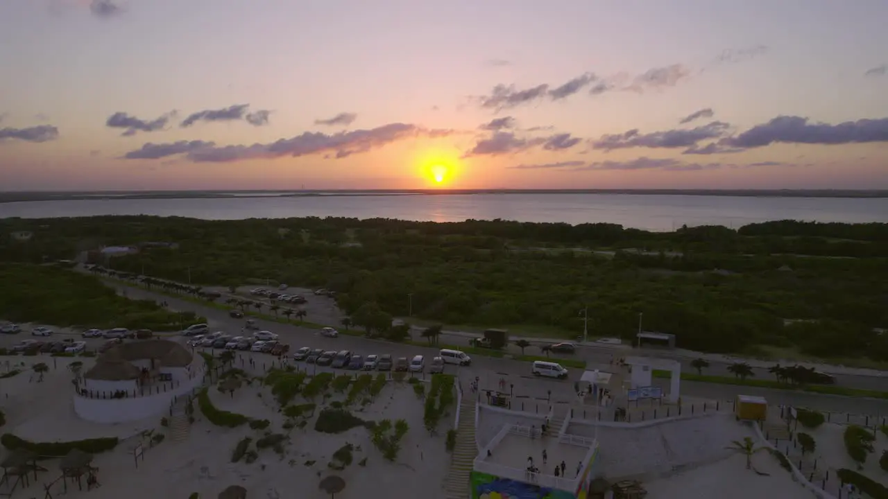 Large Bright Orange Sunset Sun On Ocean Horizon With Luxury Tourist Resorts On Shore Of Playa Delfines Cancun Mexico 4K Drone