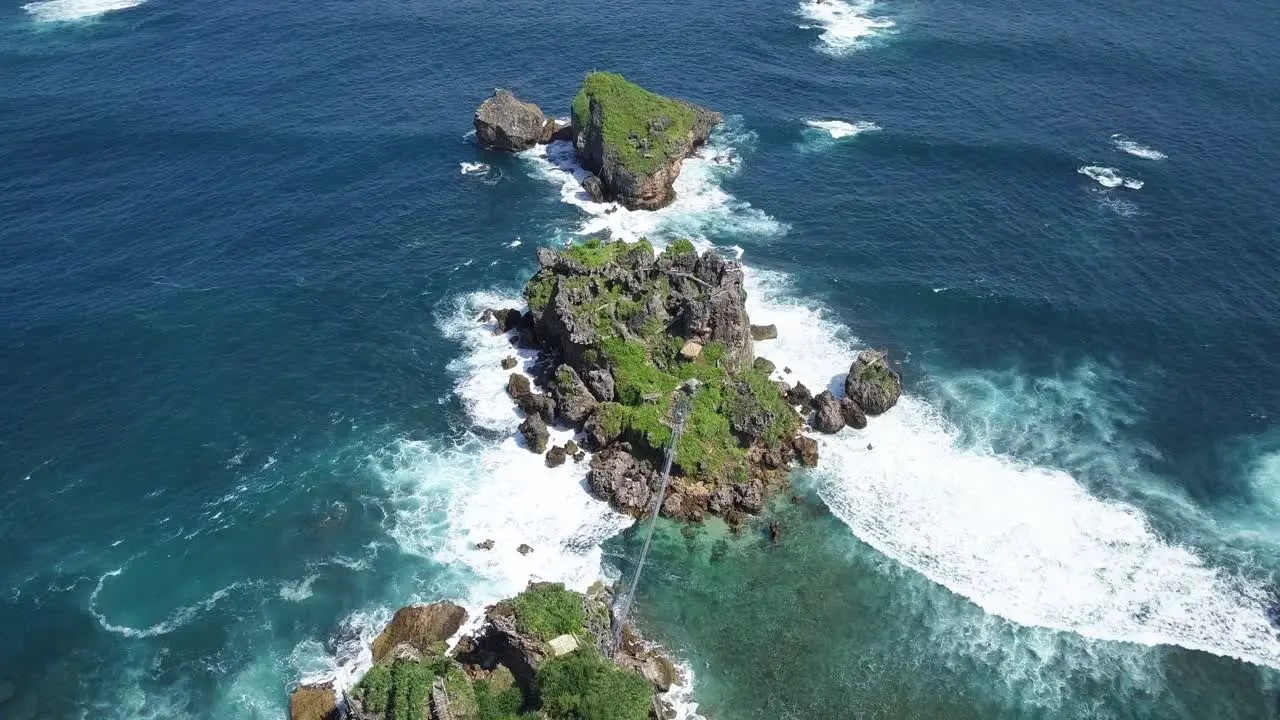 Aerial view of overgrown rocks in ocean hit by waves during sunny day TIMANG ISLAND YOGYAKARTA INDONESIA