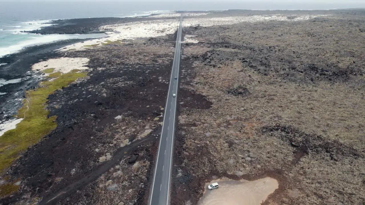 Aerial view of straight road and moving cars in volcanic coastline