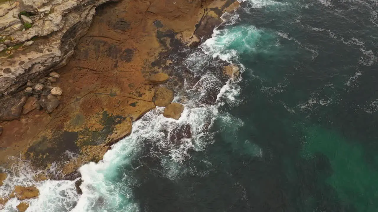 Aerial view moving north to south of Maroubra Beach north headland with unrecognisable fisherman on rocks