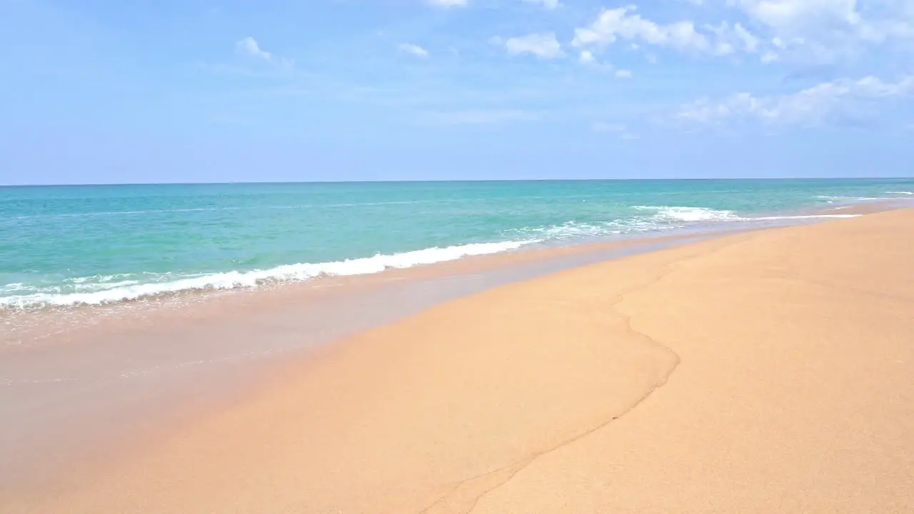 Pan waves slowly wash up on a golden tropical beach