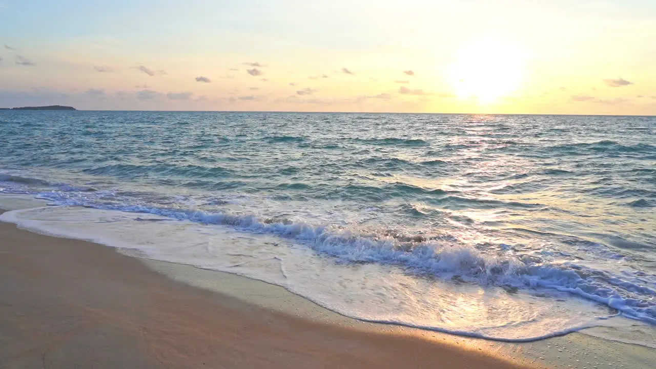 Close-up of waves crashing on a beach as the sunsets along the ocean horizon