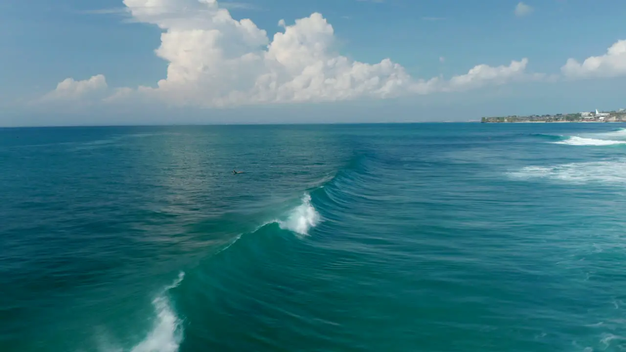 Aerial view of people surfing across the waves in tropical blue ocean Fast wave breaking across the ocean surface