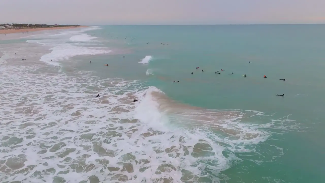 Waves crashing spread beautiful ocean mist over surfers at sunset aerial orbit