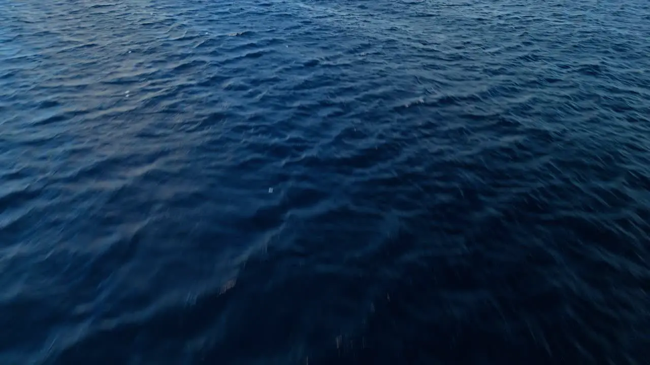 Low flying aerial above vibrant deep blue ocean ripples and current nature background