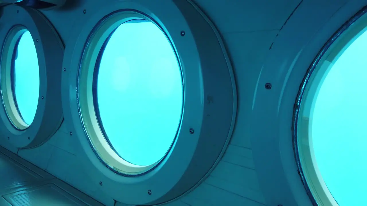 Gimbal panning shot across rows of portholes in a submarine at the bottom of the ocean off the coast of Kailua-Kona Hawai'i