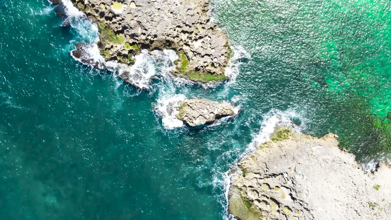 Puerto Rico green and blue water splashing against rocky island from above drone shot