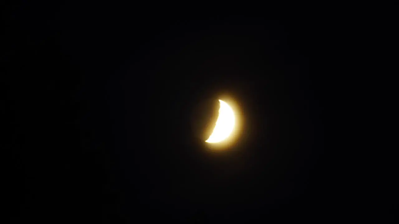 Time-lapsed tracking shot of moon moving from behind trees and through the sky with dramatic streaking clouds