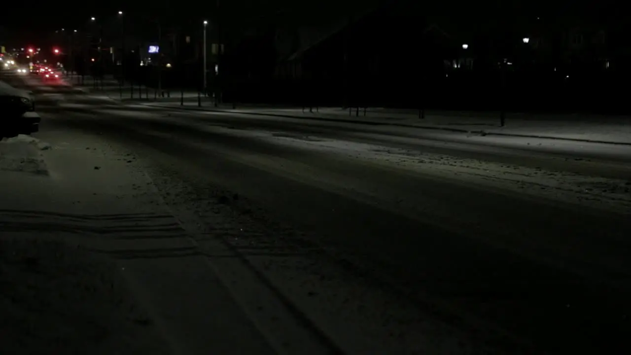 Cars driving down a main road in a suburban area during a snowstorm