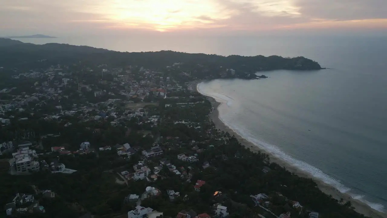 Ocean waves crash on long sandy stretch with coastal view homes in Sayulita Mexico