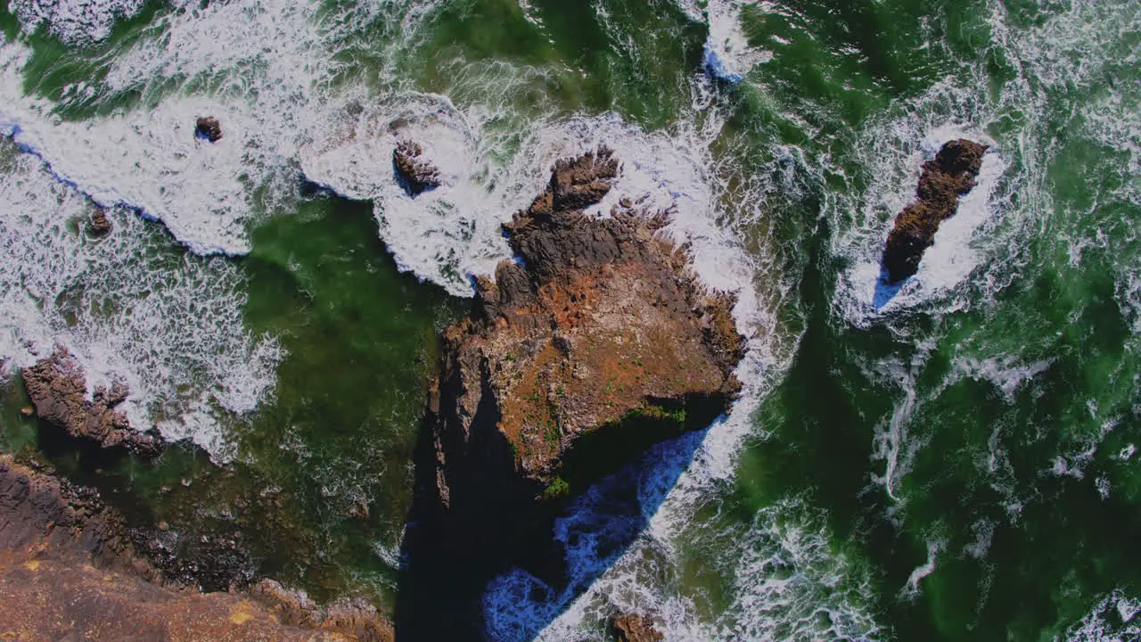 Aerial descending above ocean rock breaking waves patterns textures