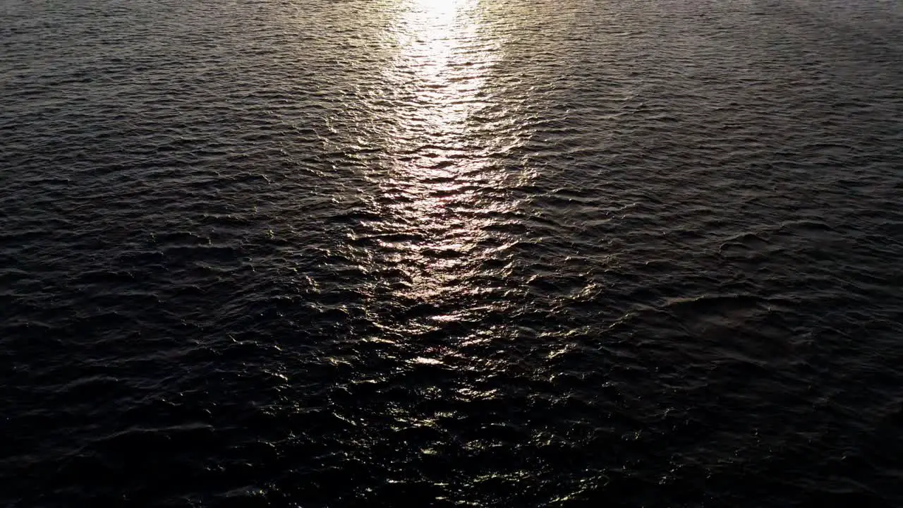 Aerial wide angle view of dark Caribbean ocean water as drone flies over to setting sun