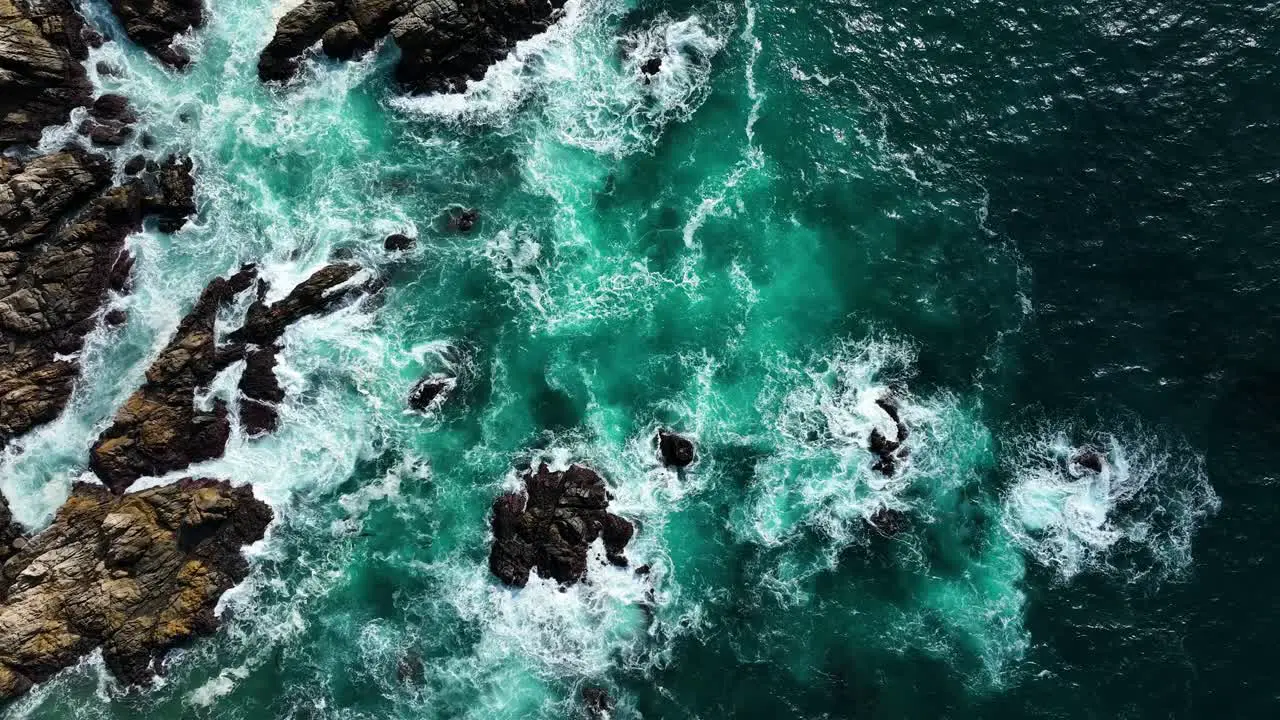 Top down view of deep blue waves crashing on brown rocks Slow motion Big Sur California