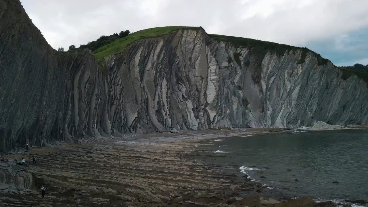 Ocean waves crash on jagged rocky Playa de Sakoneta basque county Spain aerial time lapse